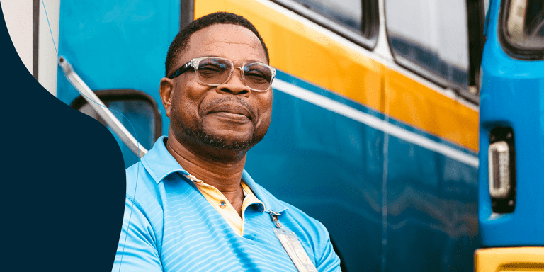 Afro-descendant man smiling warmly, with several buses visible in the background - Inter-American Development Bank IDB - Impact Development